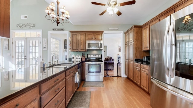 kitchen with a sink, visible vents, appliances with stainless steel finishes, light wood finished floors, and brown cabinetry