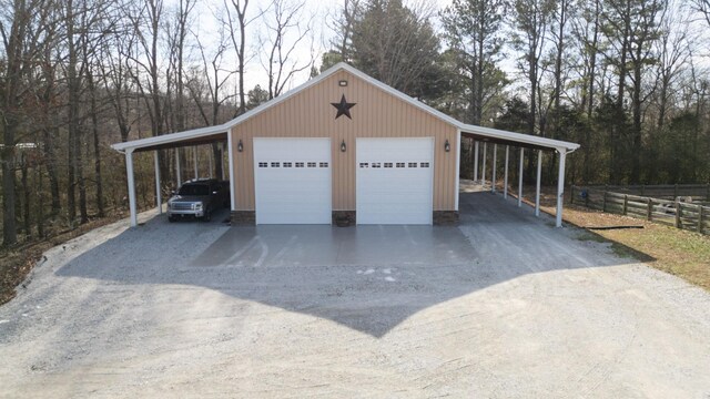 garage featuring a garage, fence, and driveway