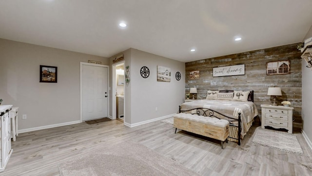 bedroom featuring light wood finished floors, wooden walls, baseboards, and recessed lighting