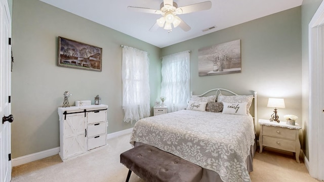 bedroom featuring a ceiling fan, light carpet, visible vents, and baseboards