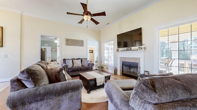 living area with a tile fireplace, baseboards, crown molding, and wood finished floors