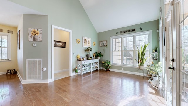 entryway with plenty of natural light, wood-type flooring, visible vents, and high vaulted ceiling