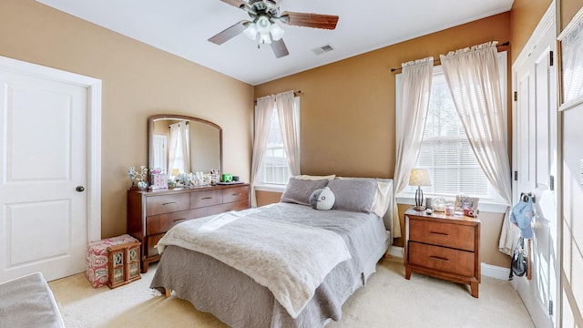 bedroom featuring multiple windows, visible vents, a ceiling fan, and light colored carpet