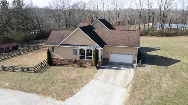 view of front facade featuring driveway, a chimney, an attached garage, fence, and a front lawn