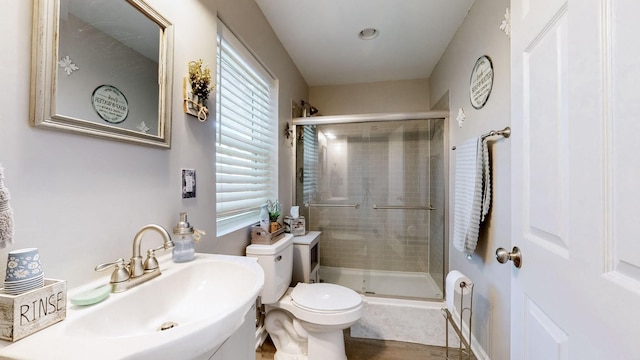 bathroom with wood finished floors, a stall shower, a sink, and toilet