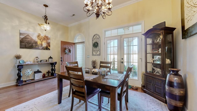 dining space with french doors, crown molding, visible vents, wood finished floors, and baseboards