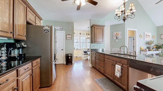 kitchen featuring stainless steel appliances, brown cabinets, a sink, and light wood finished floors