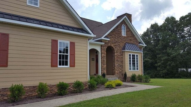 property entrance featuring a standing seam roof, a yard, and metal roof