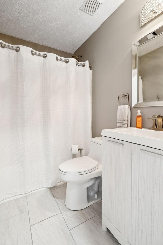 bathroom featuring a shower with curtain, vanity, toilet, and a textured ceiling