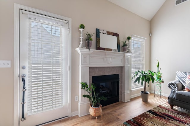 living room featuring lofted ceiling, light wood-type flooring, and a fireplace