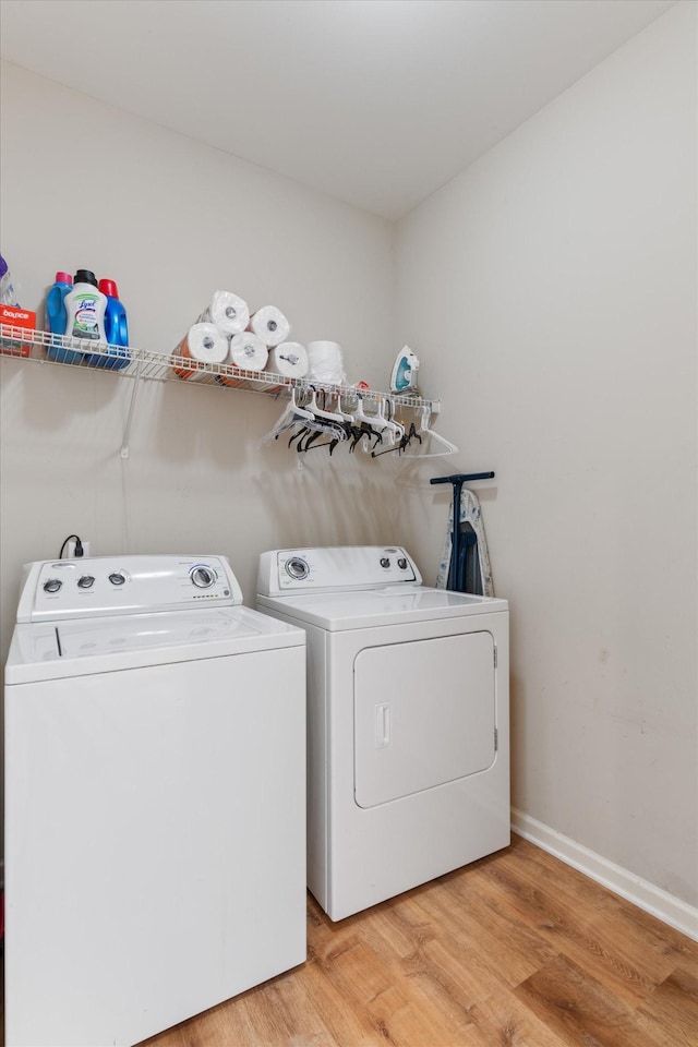 clothes washing area with hardwood / wood-style flooring and washer and clothes dryer