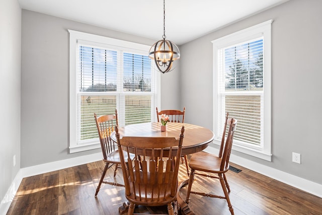 dining area with dark hardwood / wood-style floors and an inviting chandelier