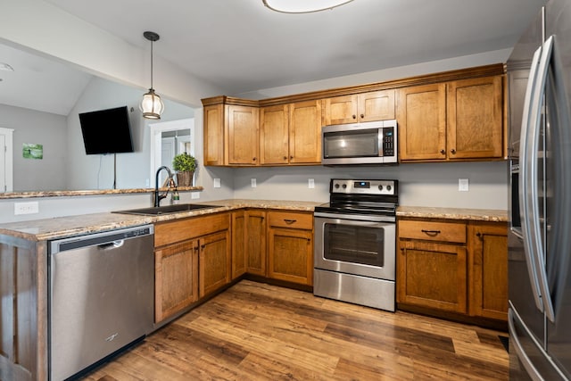 kitchen featuring sink, stainless steel appliances, dark hardwood / wood-style floors, decorative light fixtures, and kitchen peninsula