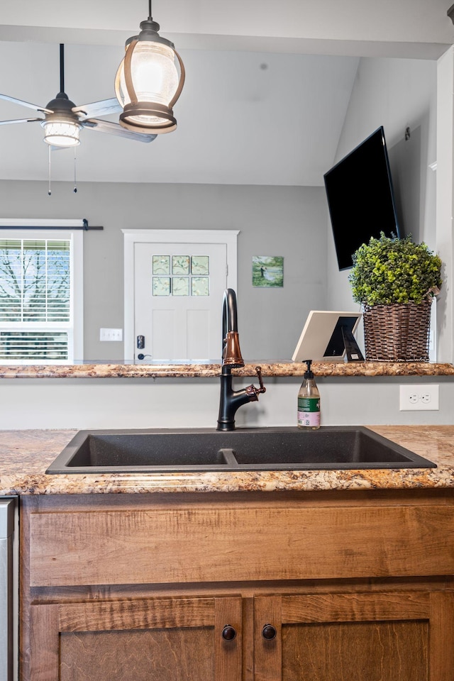 kitchen with vaulted ceiling, ceiling fan, sink, and hanging light fixtures