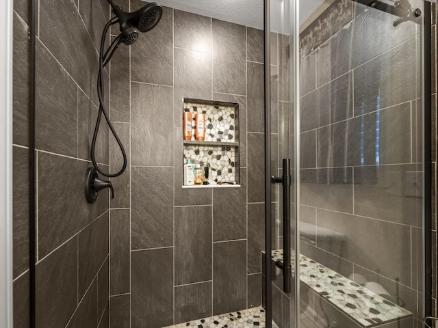 bathroom featuring a shower with door and a textured ceiling