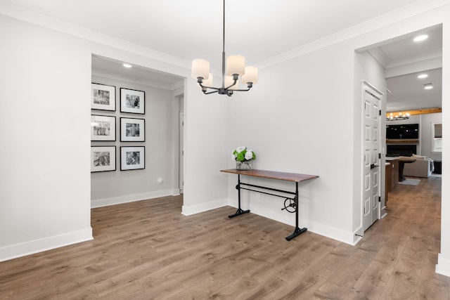 dining space featuring crown molding, wood-type flooring, and a notable chandelier