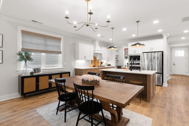 dining space featuring ornamental molding, sink, light hardwood / wood-style flooring, and a notable chandelier