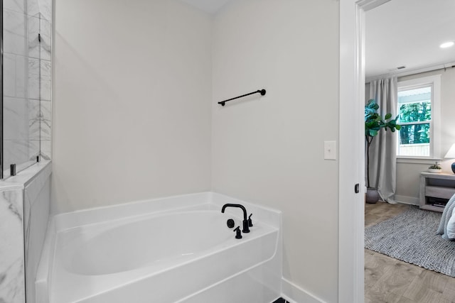 bathroom with a bath and hardwood / wood-style floors