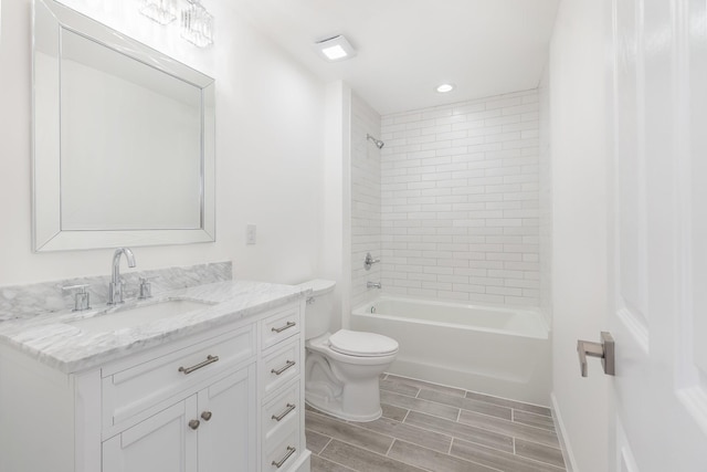 full bathroom featuring tiled shower / bath, vanity, and toilet