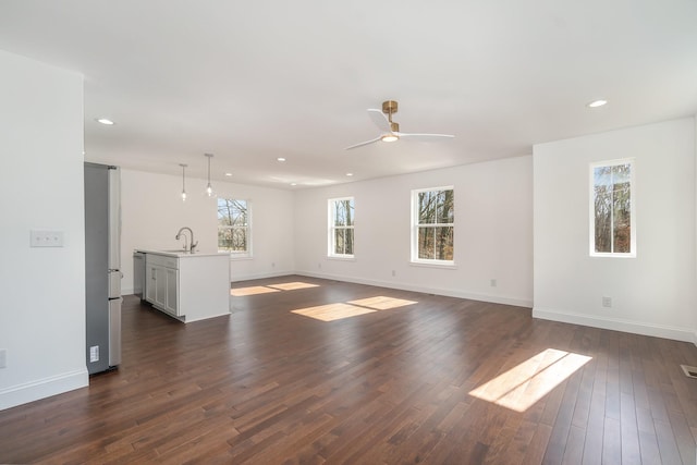 unfurnished living room featuring ceiling fan, dark hardwood / wood-style flooring, and sink