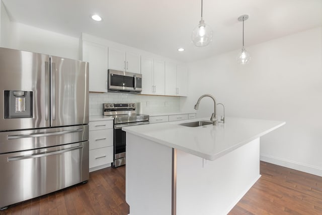 kitchen featuring sink, appliances with stainless steel finishes, a kitchen island with sink, hanging light fixtures, and white cabinets