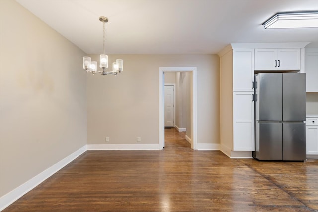 unfurnished dining area with a chandelier and dark hardwood / wood-style flooring