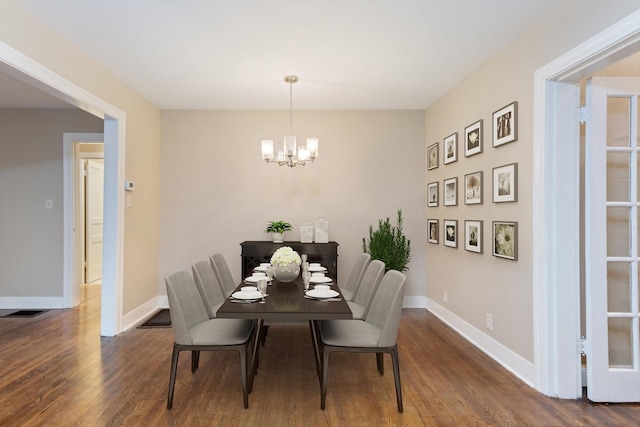 dining space with dark wood-type flooring and a notable chandelier