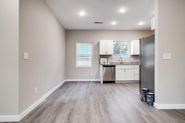 kitchen featuring fridge, stainless steel dishwasher, light stone countertops, light hardwood / wood-style floors, and white cabinets