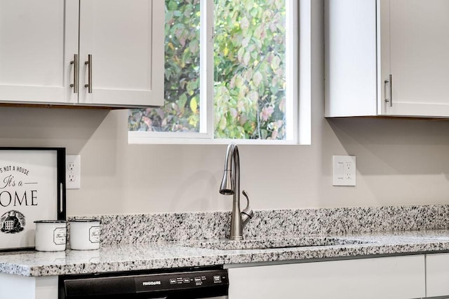 kitchen with light stone counters, sink, black dishwasher, and white cabinets