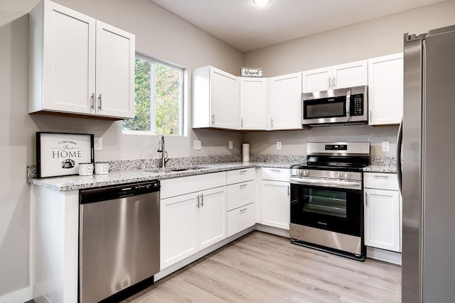 kitchen featuring white cabinetry, appliances with stainless steel finishes, sink, and light stone counters