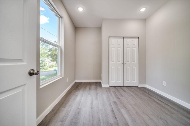 unfurnished bedroom with multiple windows, a closet, and light wood-type flooring