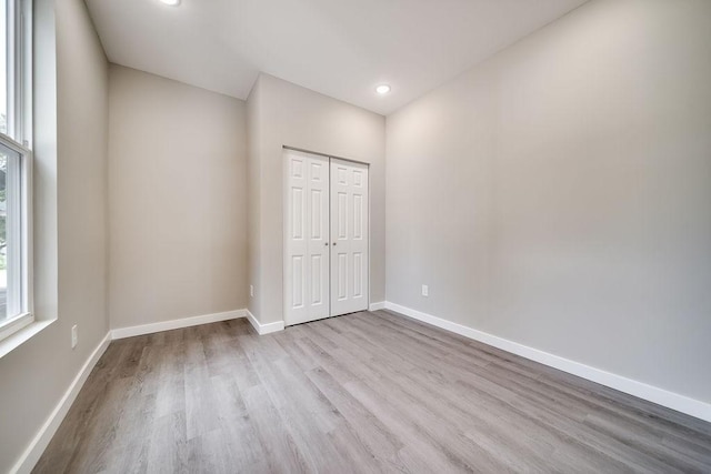 unfurnished bedroom with light wood-type flooring and a closet