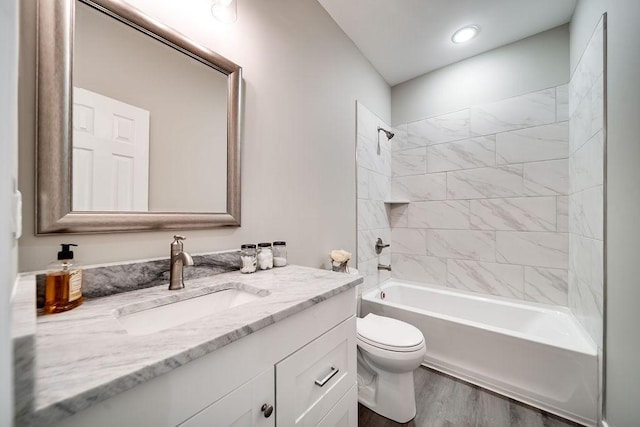 full bathroom featuring tiled shower / bath, wood-type flooring, vanity, and toilet