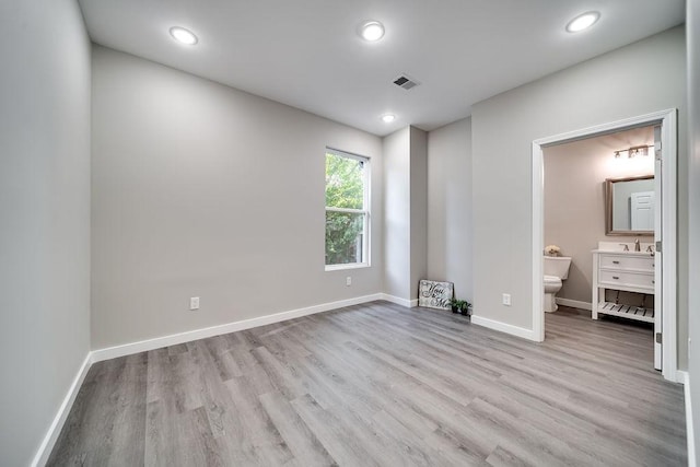 unfurnished bedroom featuring light wood-type flooring and ensuite bath