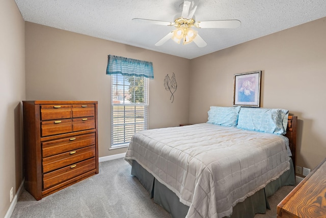 bedroom with a textured ceiling, light colored carpet, and ceiling fan