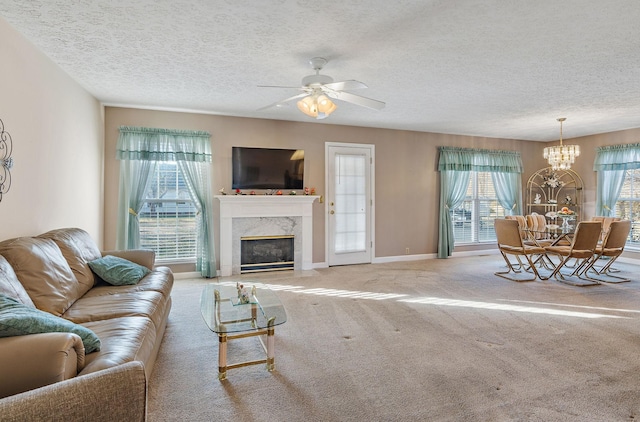 carpeted living room with a fireplace, ceiling fan with notable chandelier, and a textured ceiling