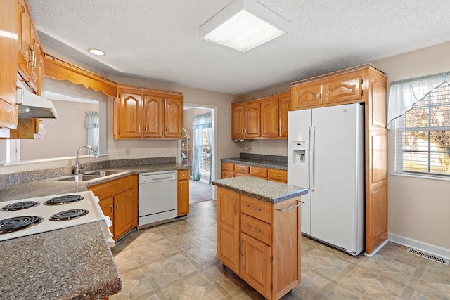 kitchen with white appliances, sink, a kitchen island, and a textured ceiling