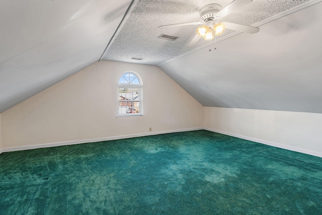 additional living space featuring dark colored carpet, lofted ceiling, ceiling fan, and a textured ceiling