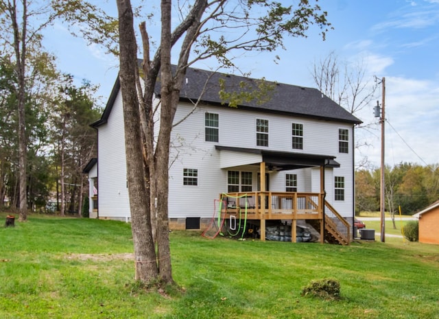 back of house featuring cooling unit, a wooden deck, and a lawn