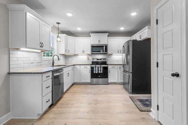 kitchen with sink, white cabinetry, light stone counters, stainless steel appliances, and light hardwood / wood-style floors