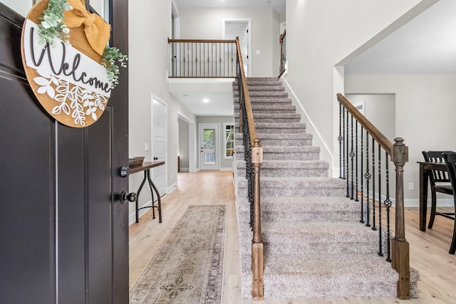 entryway featuring a towering ceiling and light hardwood / wood-style flooring