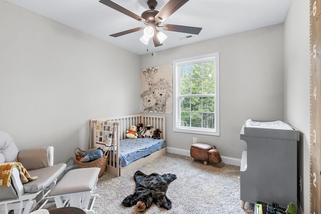 bedroom featuring ceiling fan, carpet floors, and a crib