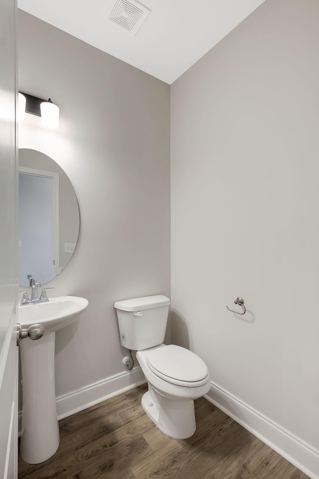 bathroom with hardwood / wood-style flooring and toilet