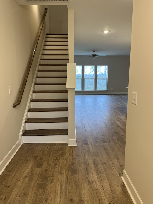 staircase with hardwood / wood-style floors and ceiling fan