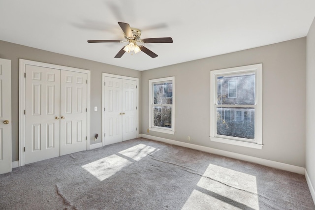 unfurnished bedroom featuring ceiling fan, carpet, and two closets