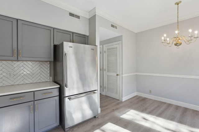 kitchen with gray cabinets, light hardwood / wood-style flooring, high end fridge, tasteful backsplash, and decorative light fixtures