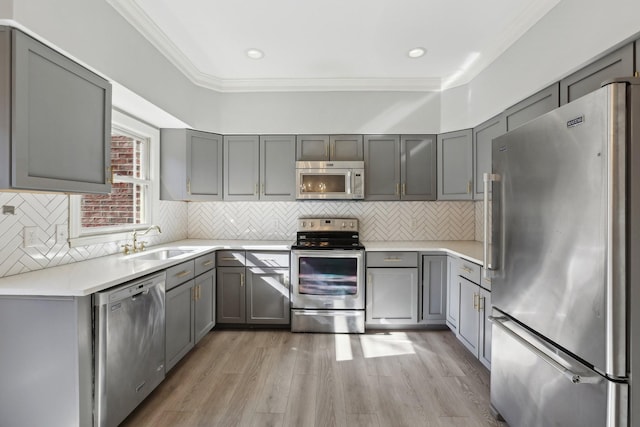 kitchen featuring tasteful backsplash, stainless steel appliances, gray cabinets, and sink