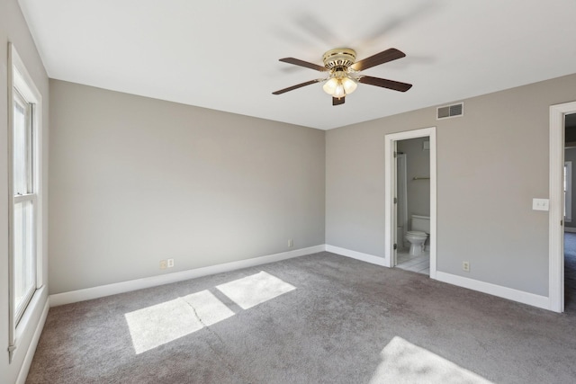 unfurnished bedroom featuring multiple windows, ensuite bathroom, a spacious closet, and ceiling fan