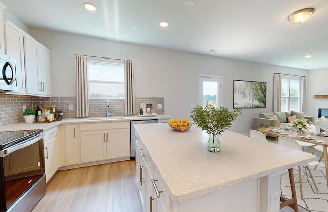 kitchen with open floor plan, stainless steel appliances, a sink, and a wealth of natural light