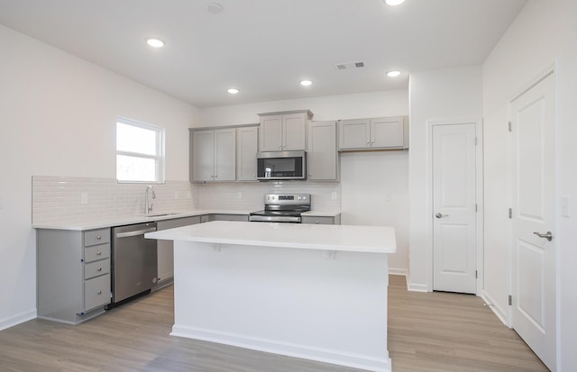 kitchen featuring appliances with stainless steel finishes, a sink, visible vents, and gray cabinetry